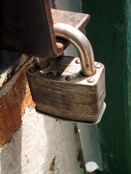 Closed padlock resting on a dark surface, standing for default credentials and API key security in AI infrastructure