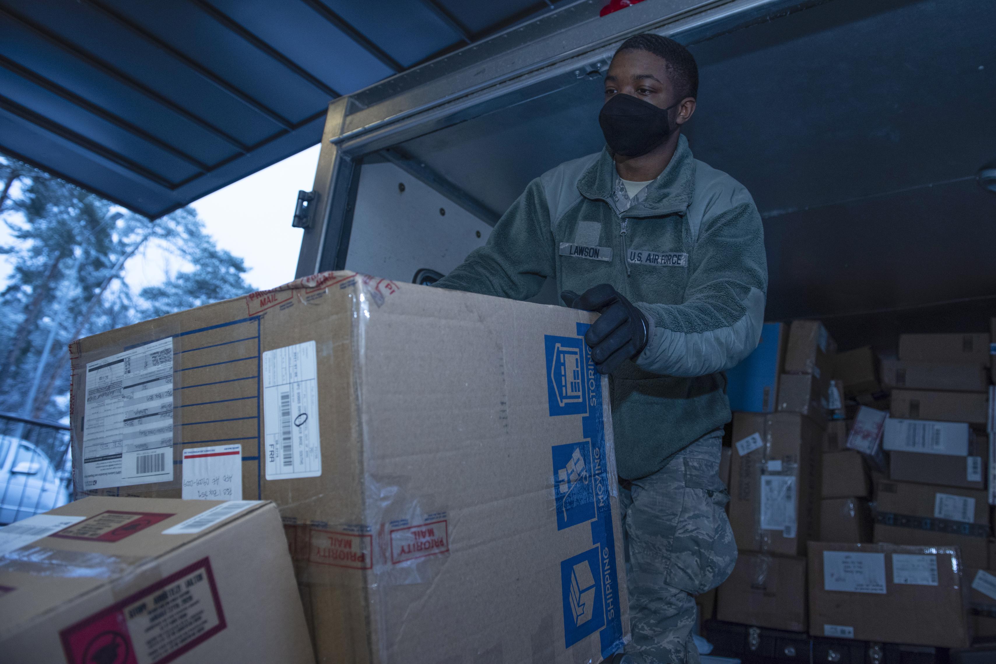 A postal clerk moving parcels onto a conveyor belt one at a time, illustrating the manual throughput step that slows down vulnerability remediation