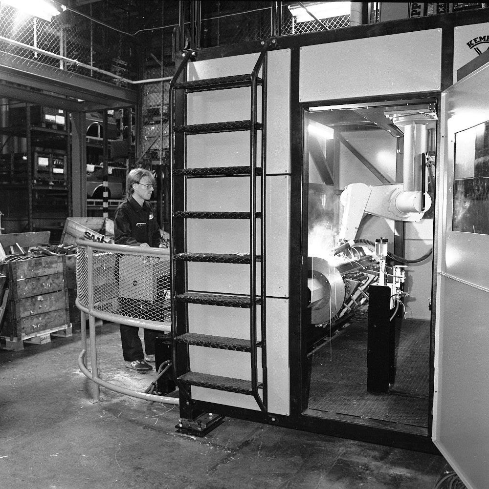A welding robot working on a vehicle body inside a car factory